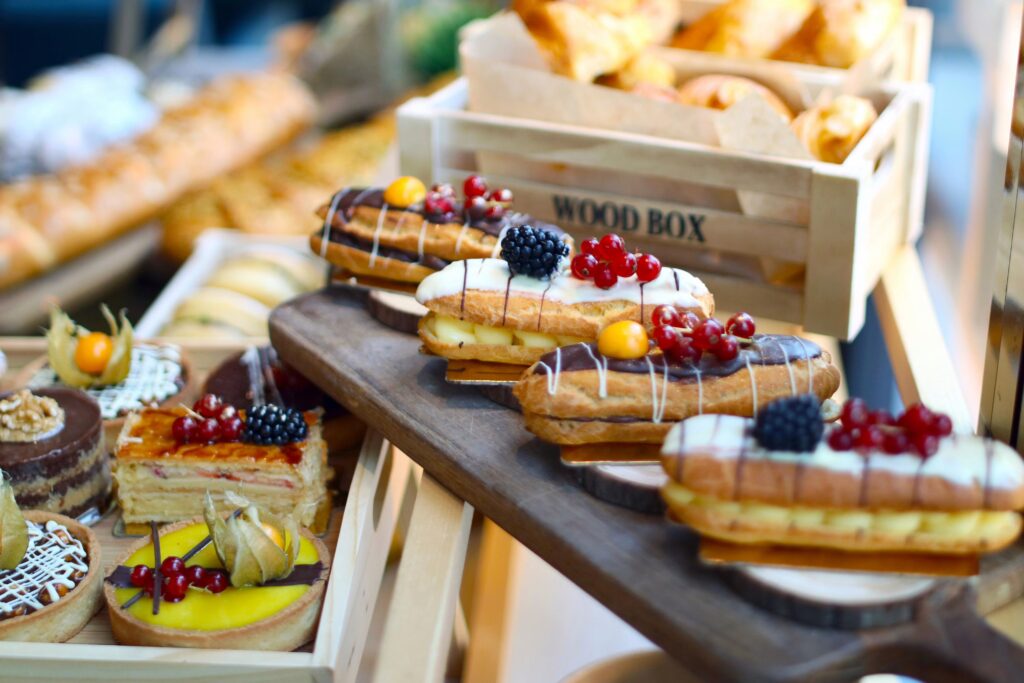 Meerdere houten plankjes met diverse desserts zoals puddingbroodjes, fruit en andere kleurrijke lekkernijen, geschikt voor een 80s party.