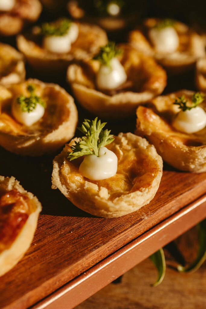 Houten plank met meerdere mini-quiches, populair retrohapje op een midden jaren 80 party.