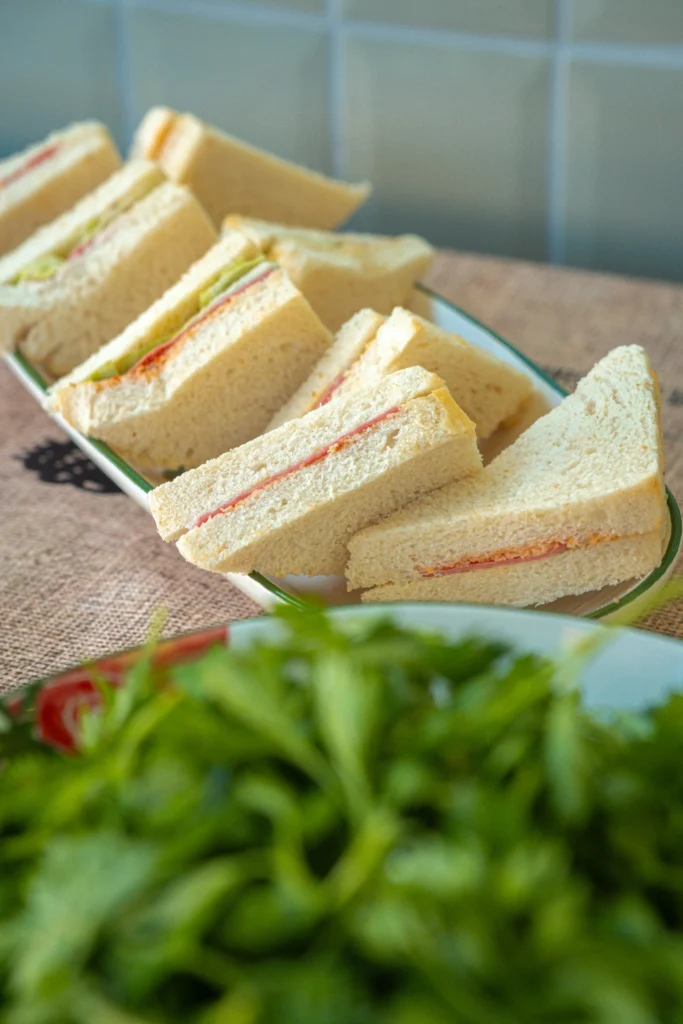 Schaal met eenvoudige sandwiches met vleeswaren en sla zoals geserveerd op bijeenkomsten in de jaren 40.