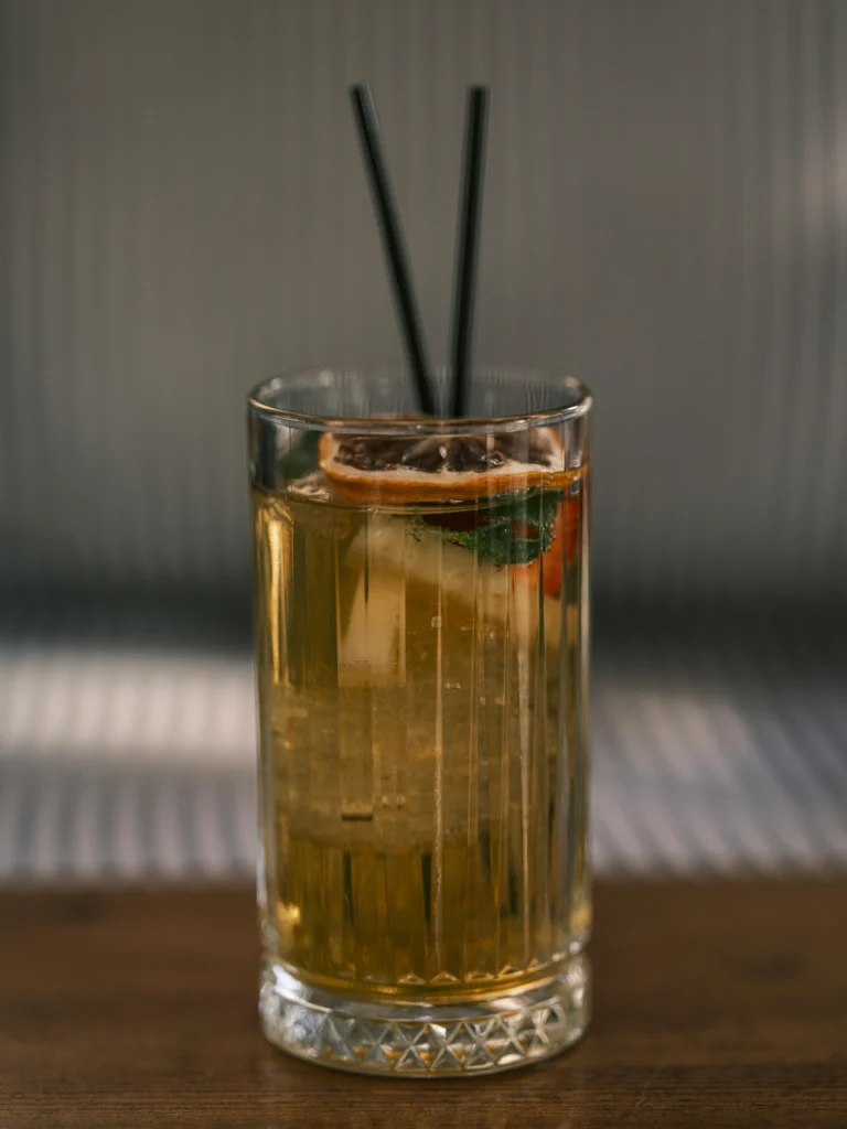 Whiskey highball cocktail in een decoratief glas met gedroogd bloedsinaasappelschijfje als garnish.