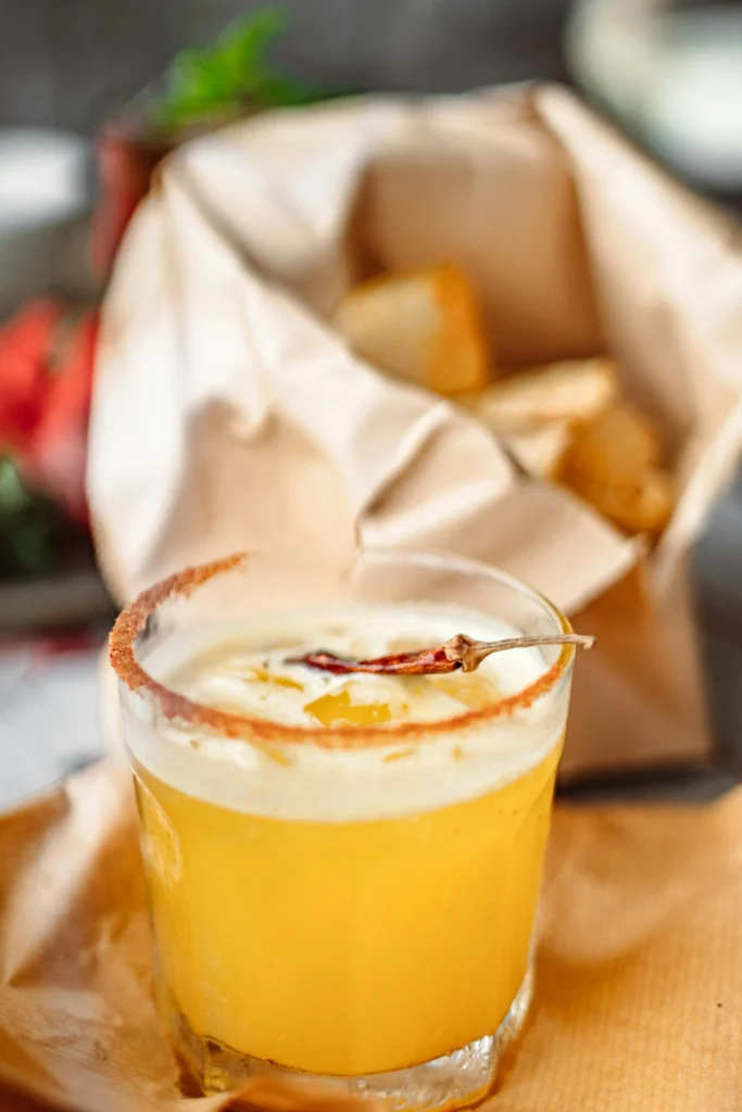 Whiskey Sour cocktail uit de jaren 50 in een laag glas, gegarneerd met een gedroogd kruid.