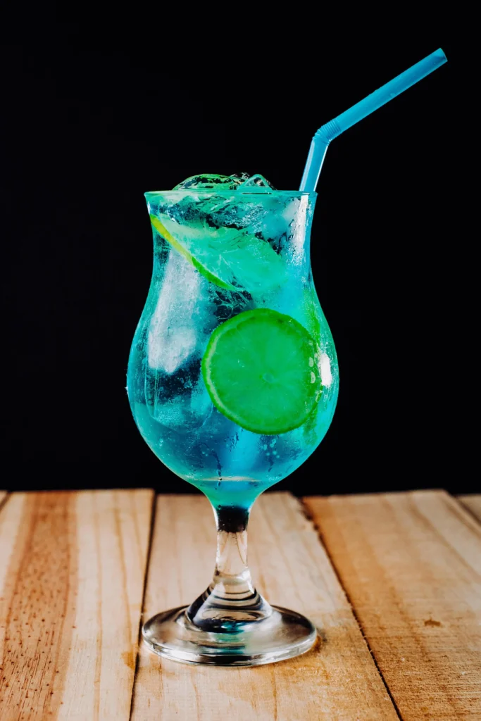 Glas Blue Lagoon cocktail met citroen en blauw rietje op een 90s feest