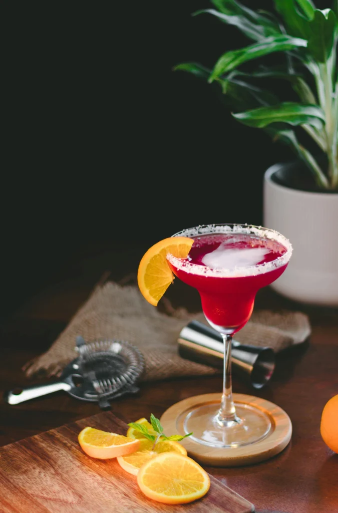 Glas cosmopolitan met sinaasappelschijfje en strainer op een 90s party