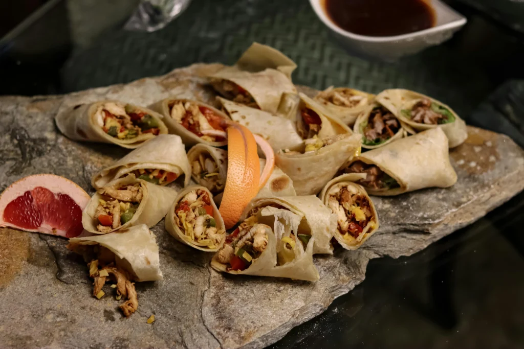 Schaal met kleine wraps gevuld met vlees en groenten op een 90s party