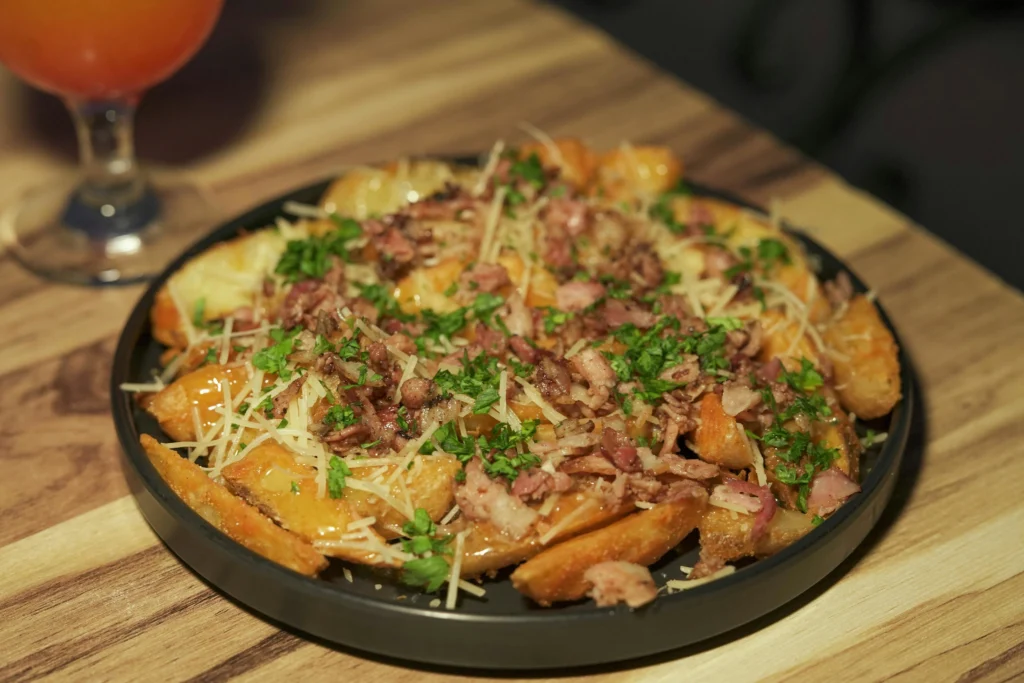 Schaal met loaded potato wedges met vlees en kaas op een 90s feest